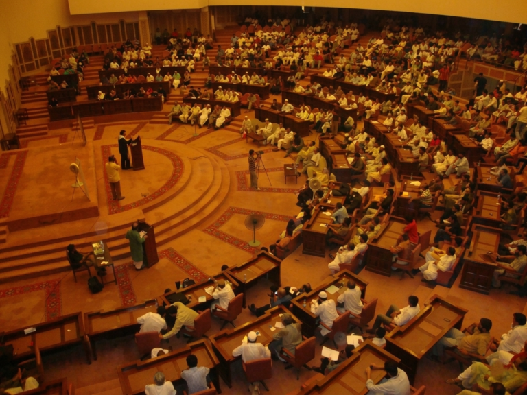Shaykh Umar Vadillo addressing a large parliamentary assembly in a semicircular chamber
